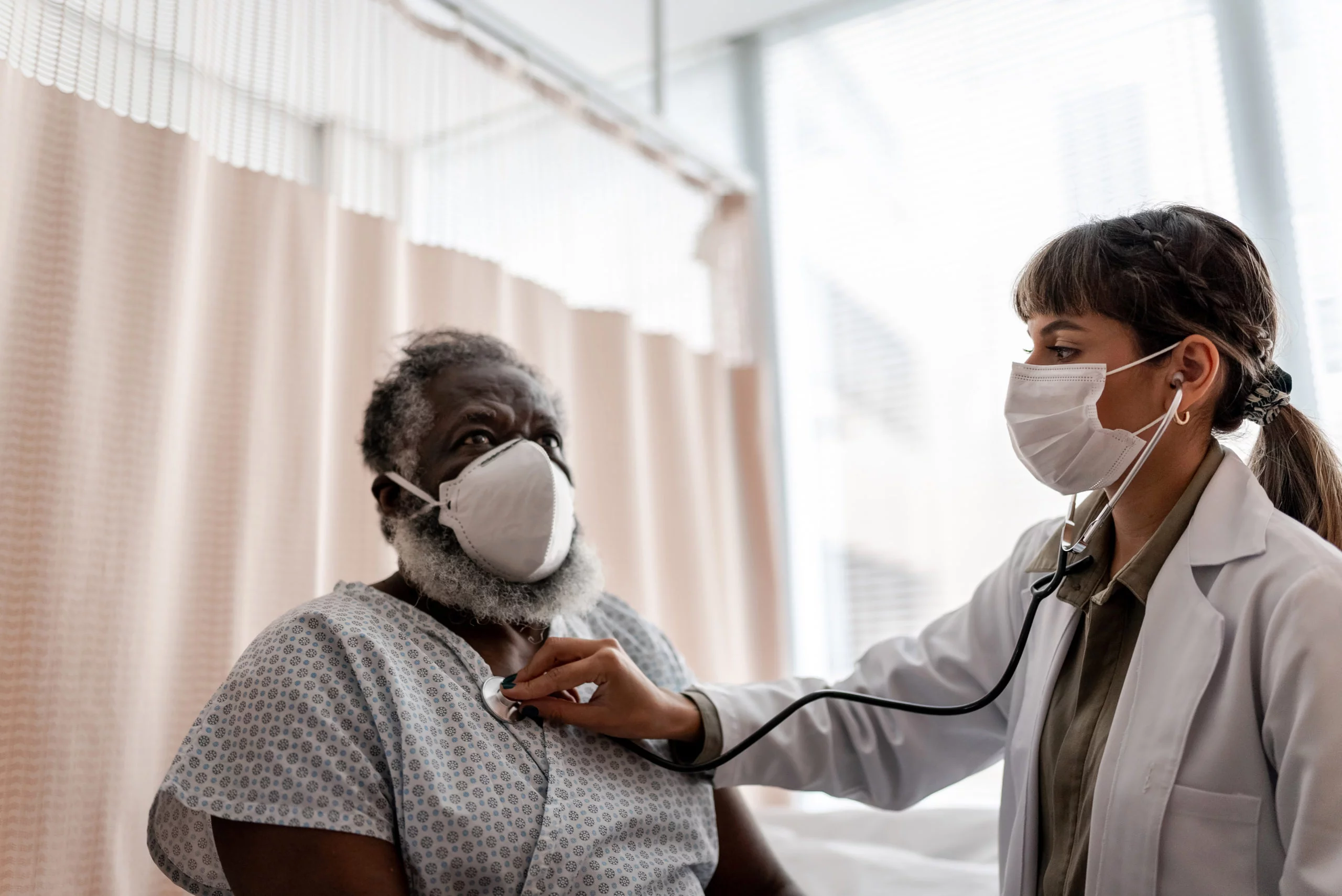 a woman doctor listening to a man's heart