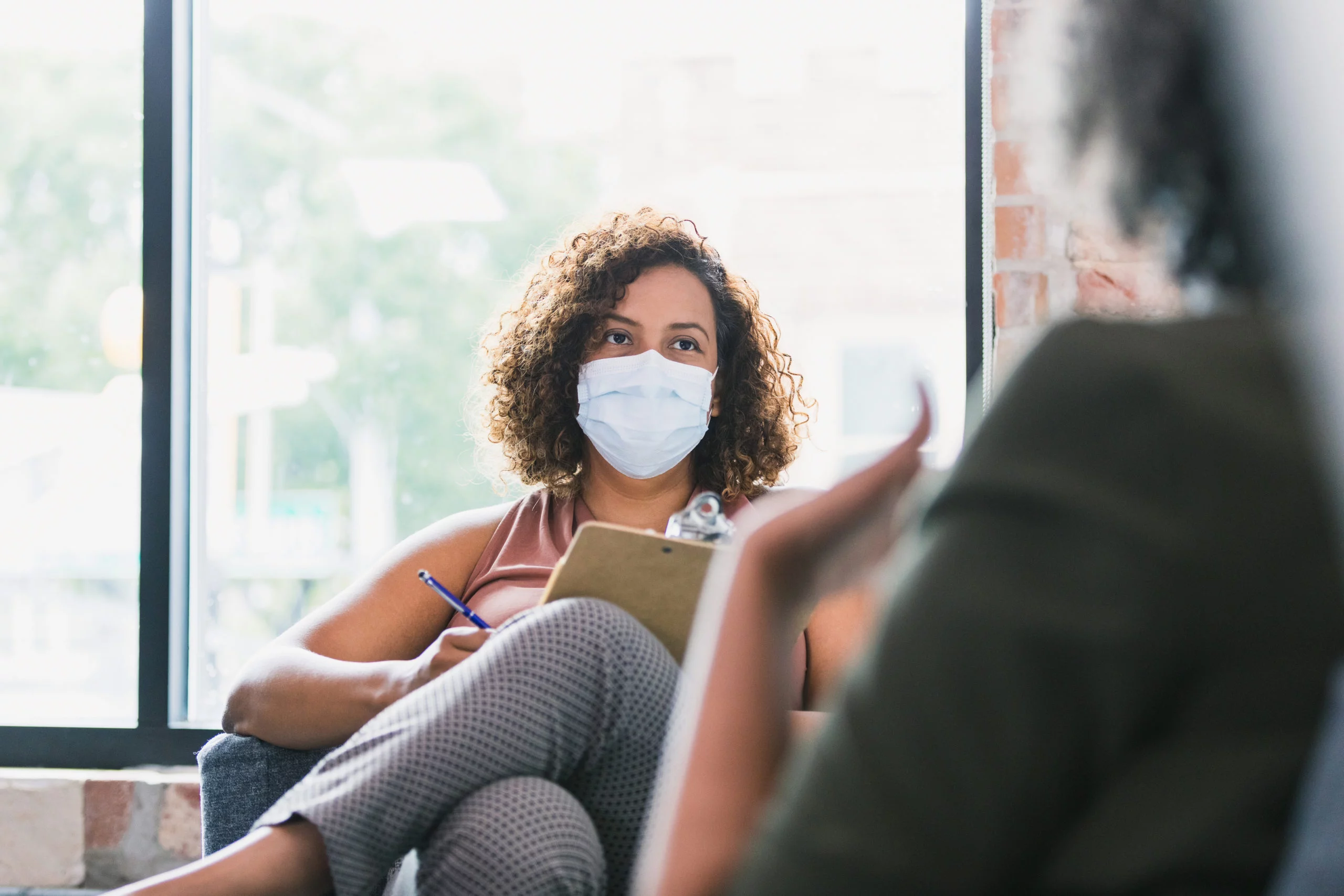 une femme masquée prend des notes