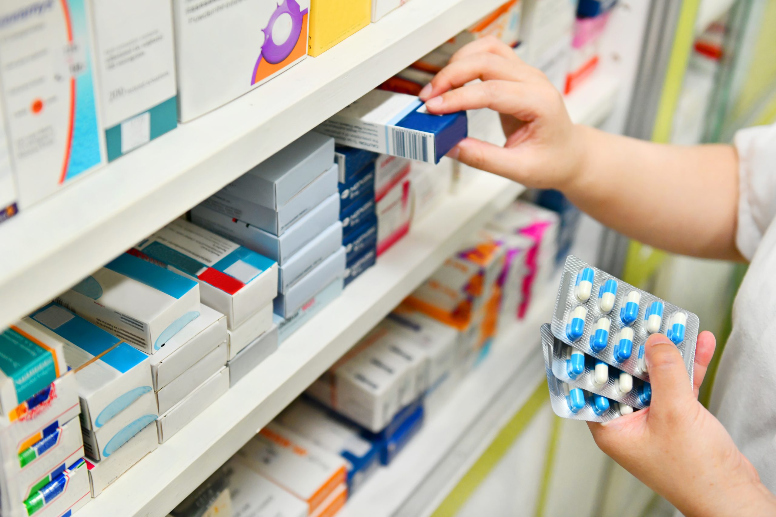 a person pulling medications off a shelf